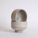 A pair of handmade earthy ice cream bowls against a white background.
