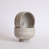 A pair of handmade earthy ice cream bowls against a white background.