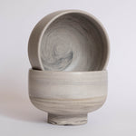 A pair of handmade earthy ice cream bowls against a white background.