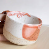 The intricate interior detail of a handcrafted ceramic cup with a handle, featuring a captivating coral red and white finish.