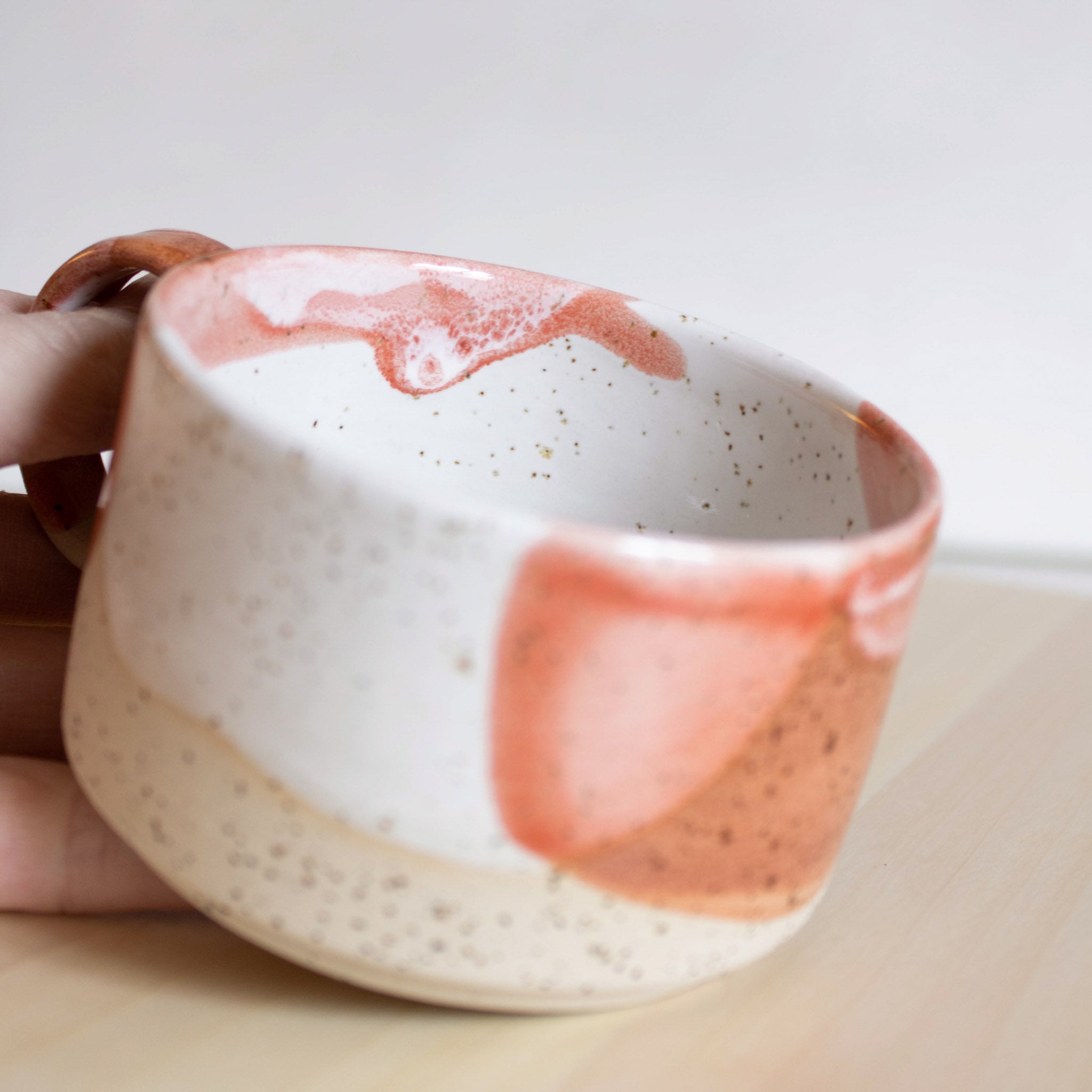 The intricate interior detail of a handcrafted ceramic cup with a handle, featuring a captivating coral red and white finish.