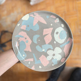 Hand holding a handcrafted ceramic plate during a creative clay collage workshop by Made of Dust.