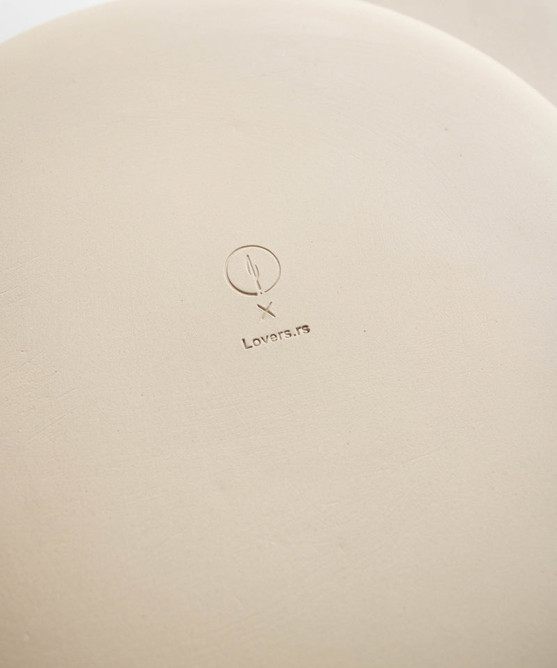 The reverse side of a plate featuring collaboration logos impressed into the clay.