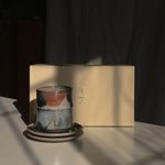 A stack of two ceramic cups on two matching saucers beside a cream-colored Special Occasion Gift Box, lit by dramatic sunlight and strong shadows.