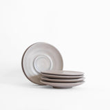 A stack of handcrafted ceramic saucer plates with a matte earthy finish, displayed on a white background.