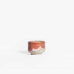 Handmade ceramic espresso cup crafted from speckled cream clay, adorned with an organic coral red and white glaze pattern, captured against a white backdrop.